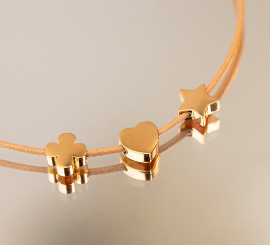 Armband mit vergoldeten Etincelle Stern, Herz, Kleeblatt am dünnen beigem Band