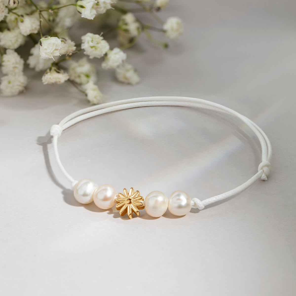 Schnurarmband weiß mit Perlen und Etincelle Blüte, vergoldet - Detailansicht