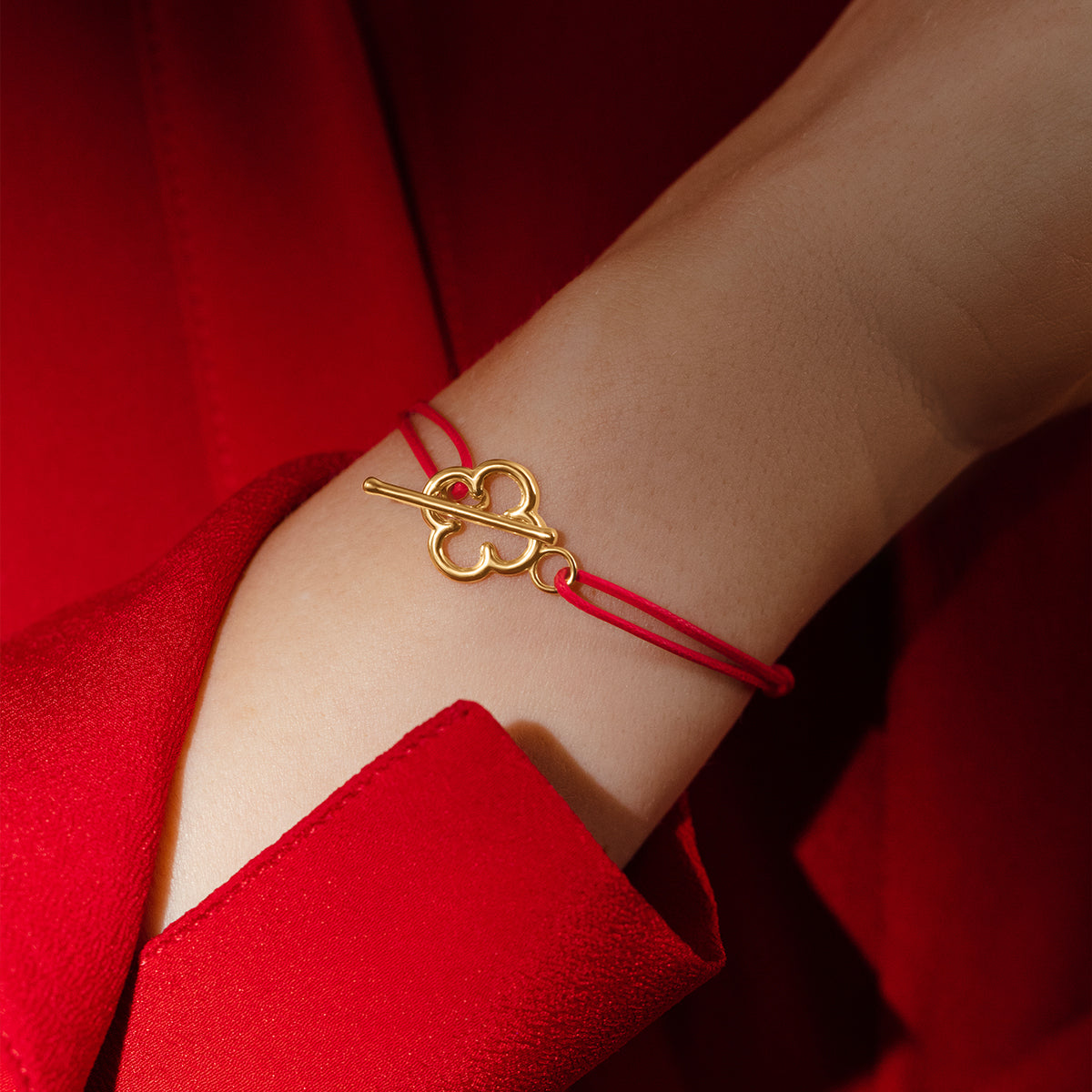 Armband mit vergoldetem Kleeblattverschluss auf roter Schnur - Detailansicht